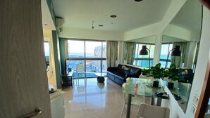 Ein modernes Wohnzimmer mit einem Glastisch, einer Couch und einem großen Fenster mit Blick auf die Stadt.