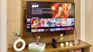 Una sala de estar moderna con un mueble bajo de madera, un televisor de pantalla plana mostrando una serie de Netflix y varios objetos decorativos.