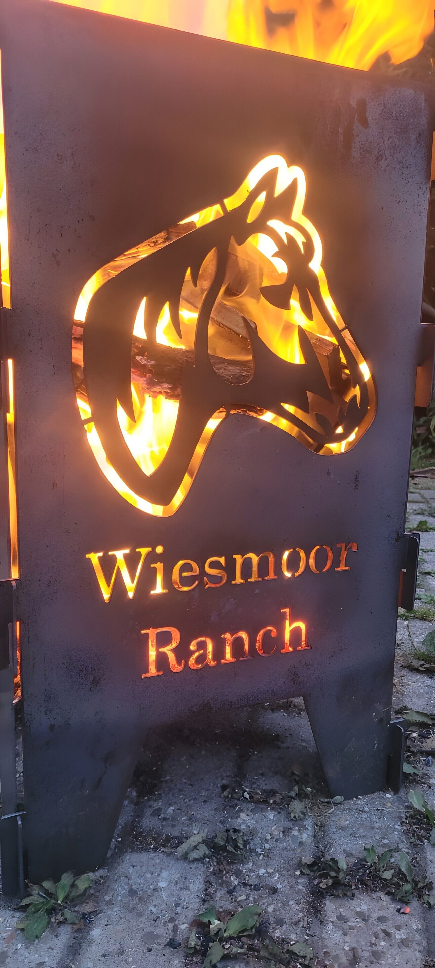 Ein Metallschild mit einer Silhouetten-Darstellung eines Pferdes und dem Text 'Wiesmoor Ranch'.