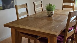 A dining room with a wooden table, chairs, a ceiling fan, and a wall-mounted light fixture. - Apartment 'Wiesmoor - Ranch' with Private Terrace, Shared Garden and Wi-Fi (Wiesmoor)