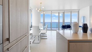 A modern kitchen with a large island, white cabinetry, and a view of the ocean.