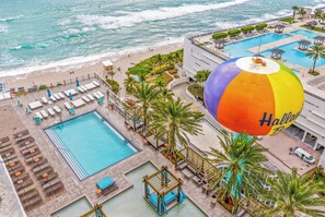 A resort with a large pool, lounge areas, and a beach view.