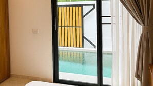 Un dormitorio con un ventanal grande, una cama y vistas a una piscina y vegetación.