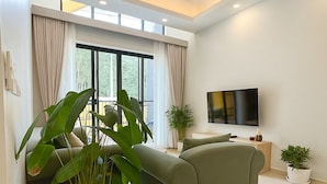 Una sala moderna con un sofá modular, un televisor de pantalla plana y plantas en macetas.