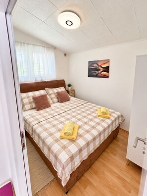 Ein Schlafzimmer mit einem Bett, einem Nachttisch, einem Bild und einer Tür.