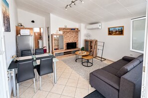 Una sala de estar moderna con un sofá, un comedor con mesa y sillas, una chimenea y un televisor.