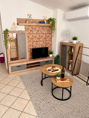 Ein modernes Wohnzimmer mit Fernseher, einer Holzunterhaltungseinrichtung und einem Kamin.