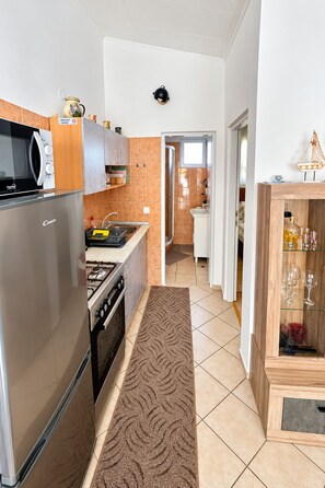 Una cocina moderna con refrigerador, estufa, microondas y un armario de madera con cristalería.