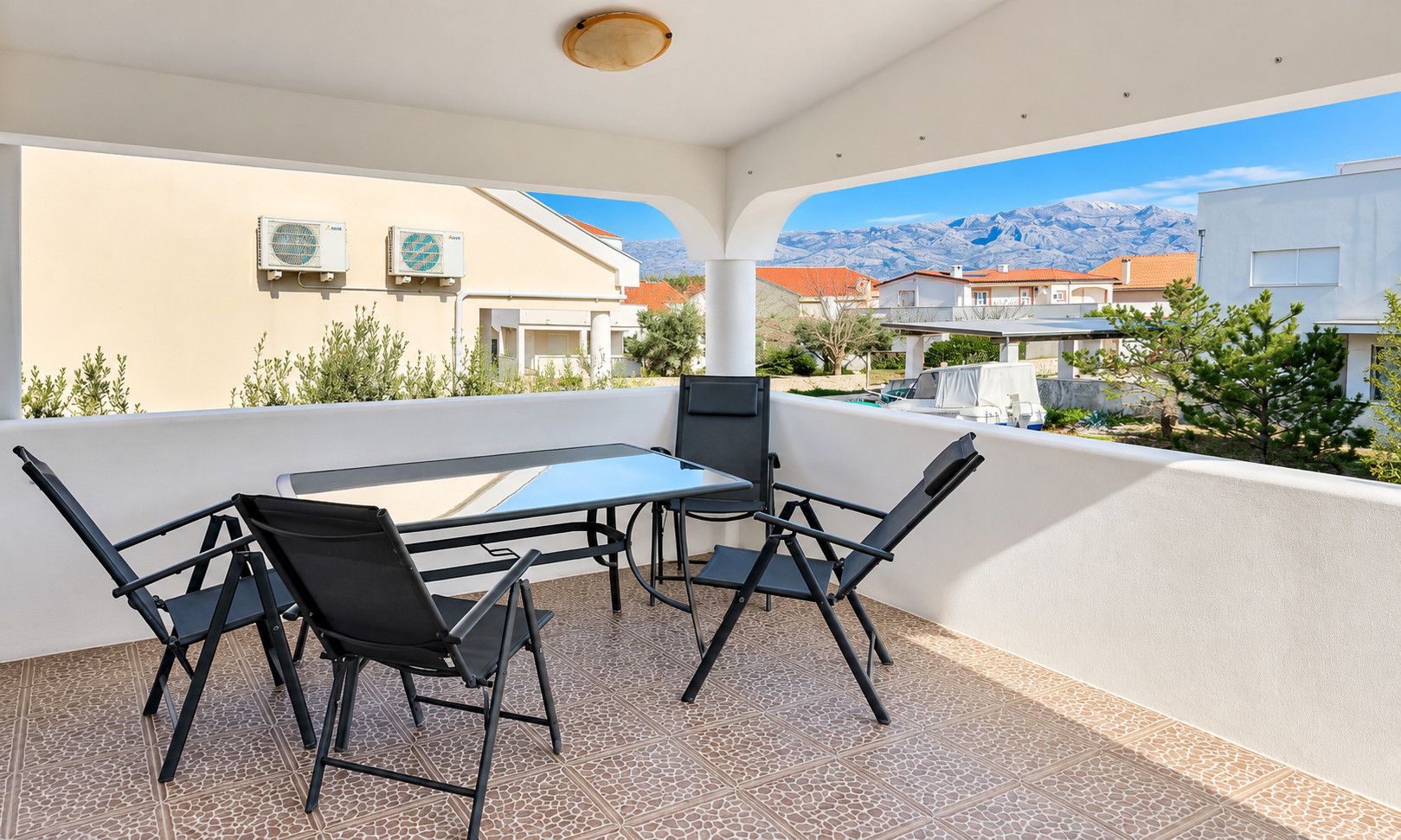 Une terrasse avec une table et des chaises, des unités de climatisation et une vue sur les montagnes.