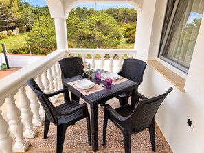 A balcony with a table set for two, chairs, and a view of the surrounding greenery. - Apartment Didovi Dvori 2 with jacuzzi (Ražanac)
