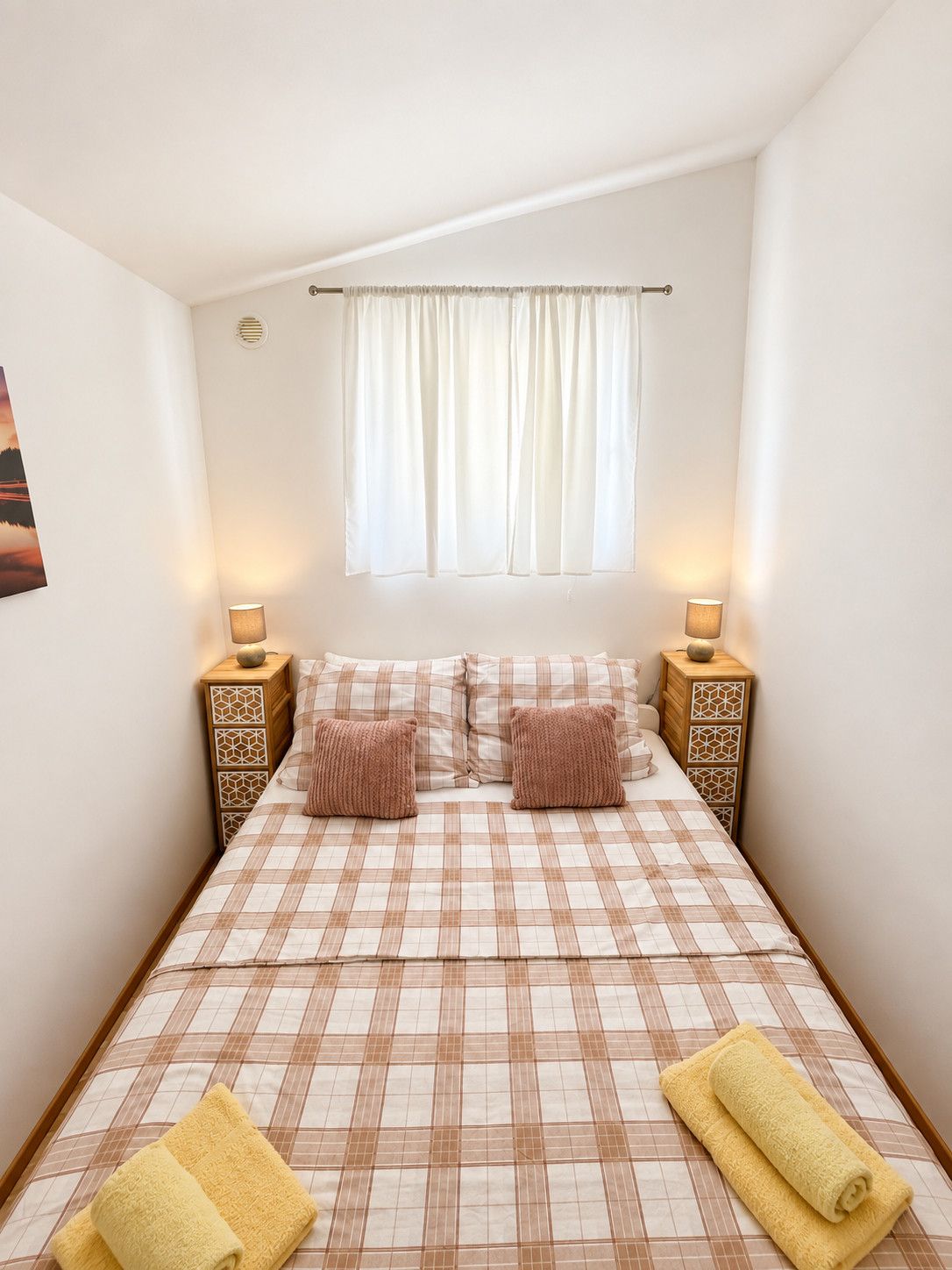 Una camera da letto con un letto, due comodini, una finestra con tende e due lampade.