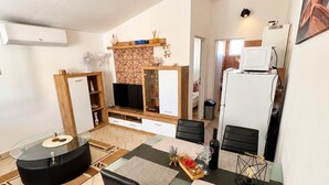 Una cocina moderna con comedor, televisor integrado y refrigerador.