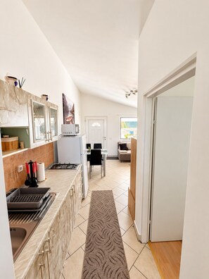 A modern kitchen with a marble countertop, a dining area with a table and chairs, and a hallway leading to a door. - Apartment Didovi Dvori 2 with jacuzzi (Ražanac)