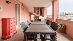 A balcony with a dining table and chairs, a red dresser, and a staircase leading to an upper level.