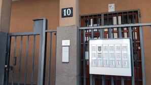 A building entrance with a metal gate, a number sign '10', and a display board with multiple informational panels. - DI TUTTO E DI PIù (Milan)