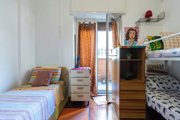A bedroom with two beds, a dresser, a radiator, and a door leading to an outdoor area. - DI TUTTO E DI PIù (Milan)