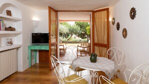 Un comedor con una mesa y sillas, televisión y vistas al exterior.