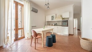 A modern kitchen with white cabinets, a dining table, and a large window with curtains.