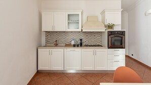 A kitchen with white cabinets, a tiled backsplash, a gas stove, and a built-in oven.