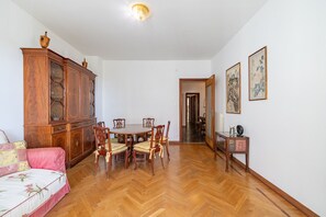 A dining area with a wooden table and chairs, a cabinet, and two framed artworks on the wall. - Porto Vecchio Apartment by Wonderful Italy (Sanremo)
