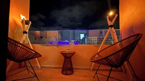 A balcony with two wicker chairs, a small table, and two candles on stands. - Charming 2-bedroom apartment in lovely Marrakesh with AC, Pool (Marrakesh)