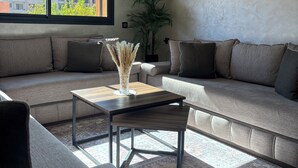 A modern living room with a sectional sofa, a coffee table, and a potted plant. - Charming 2-bedroom apartment in lovely Marrakesh with AC, Pool (Marrakesh)