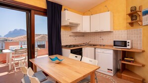 A compact kitchen with white cabinets, a microwave, and a dining area with a wooden table and chairs.