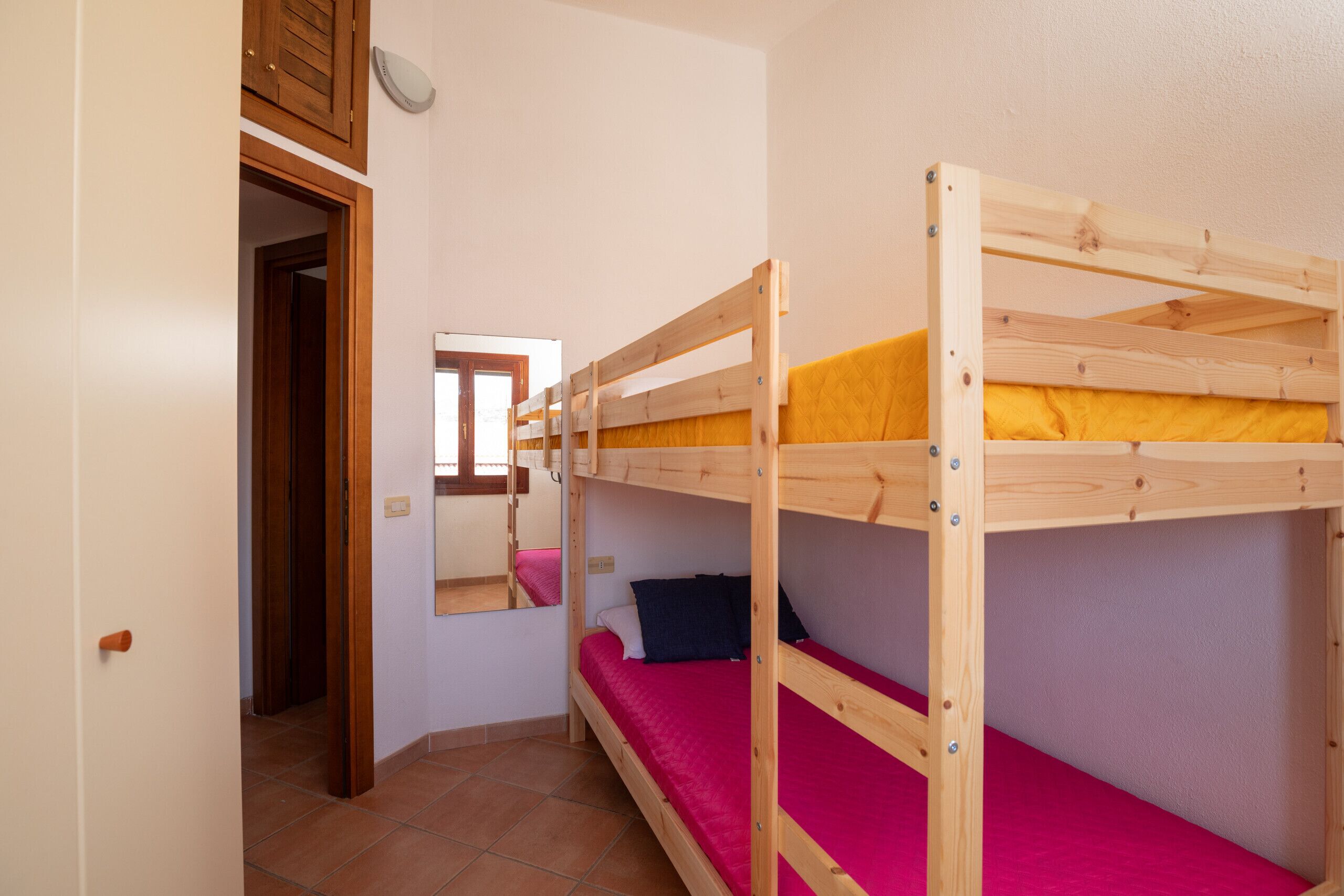 A bunk bed room with a wooden frame, a window, and a door.