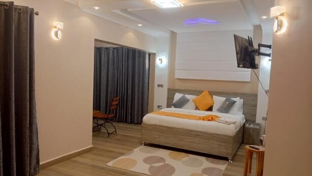 Une chambre d’hôtel moderne équipée d’un lit, d’un bureau, d’une chaise et d’un téléviseur fixé au mur.