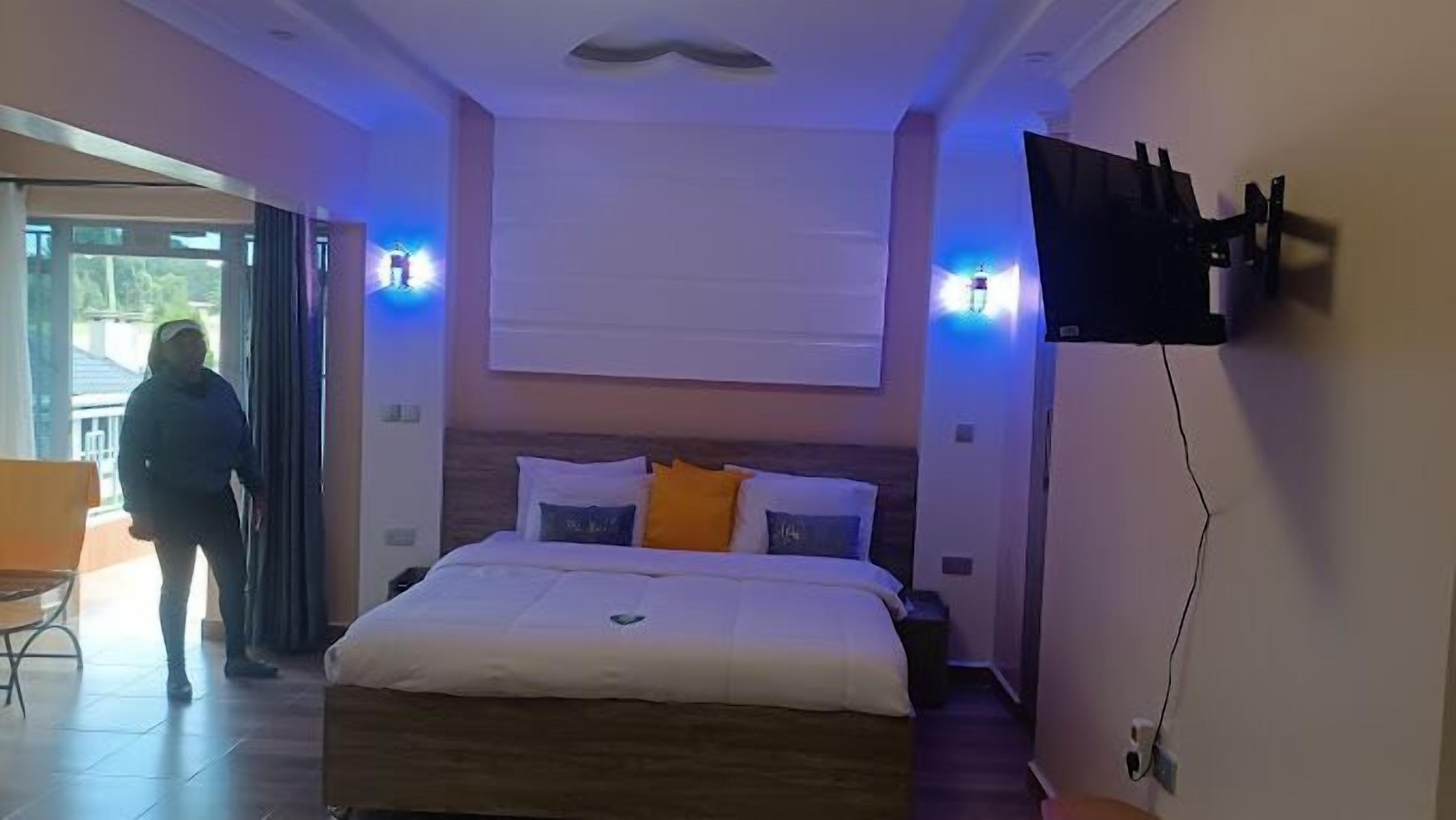 Quarto com cama, televisão na parede e porta para área externa.