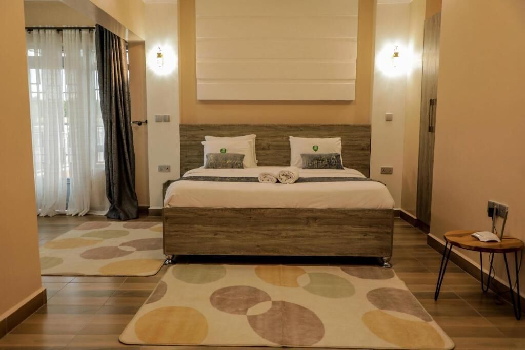 Un dormitorio con cabecera de madera, cama con ropa de cama blanca, dos lámparas de noche y una pequeña mesa con una silla.