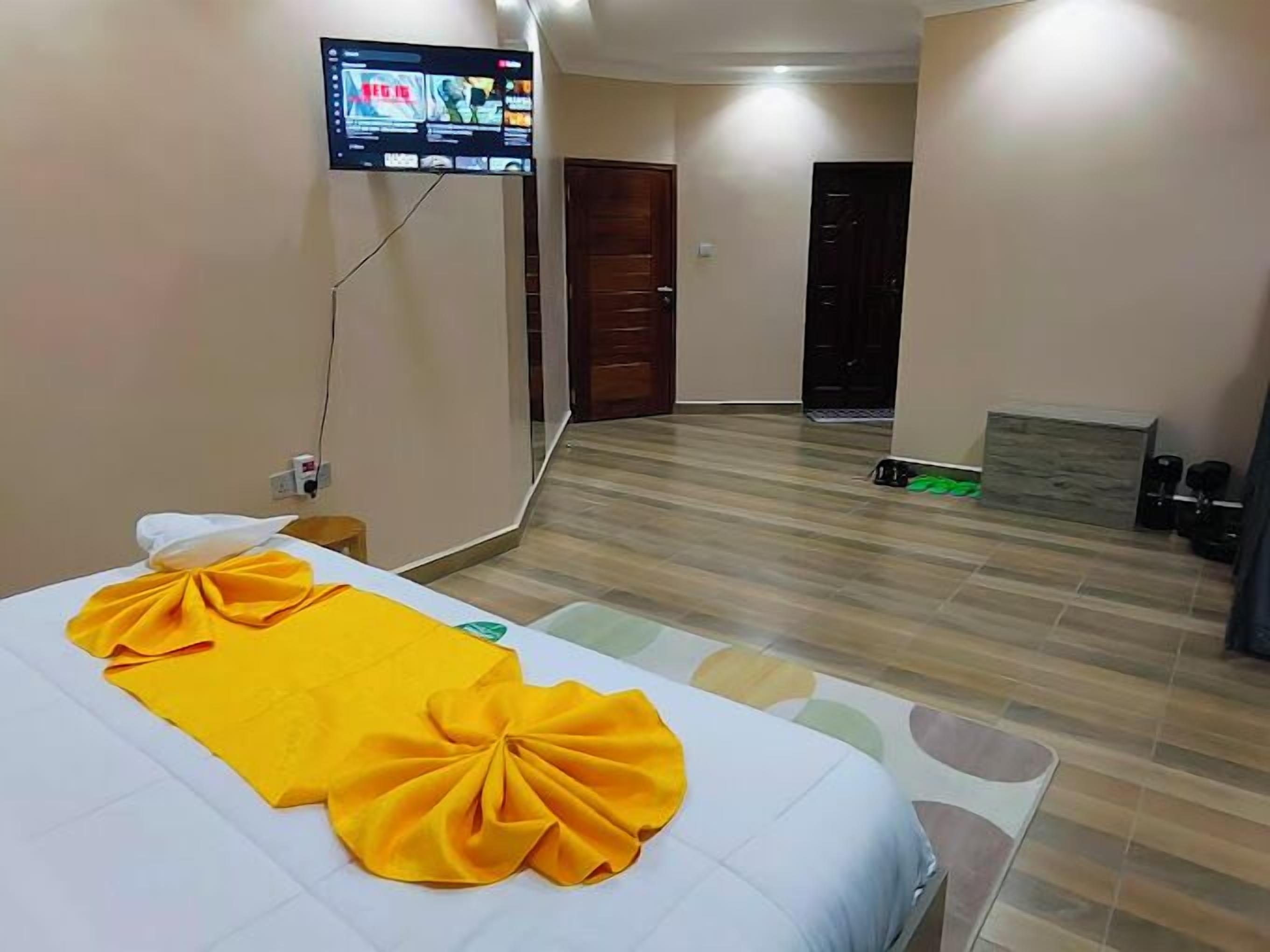 Une chambre d’hôtel avec un lit, un téléviseur fixé au mur et un plancher en bois.