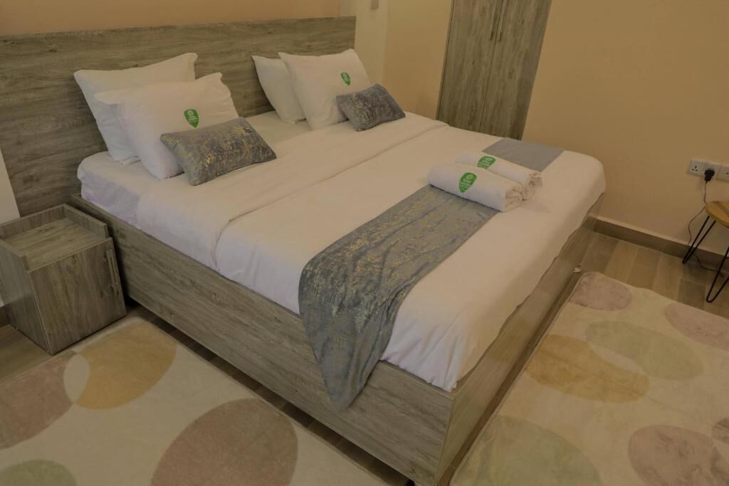 A neatly made bed with a wooden headboard, white bedding, and a grey throw blanket.