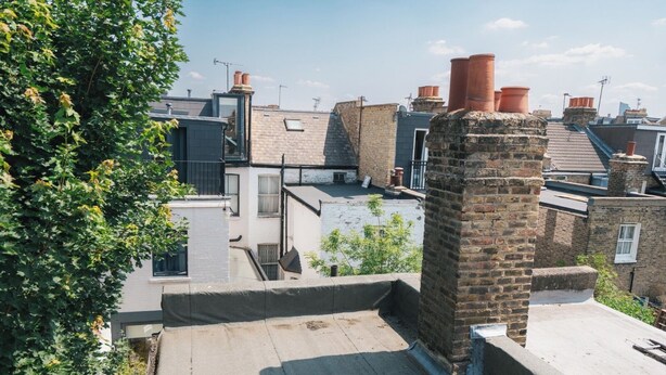A rooftop terrace with a brick chimney, a small window, and a metal railing. - Chelsea Orange Residence (London)
