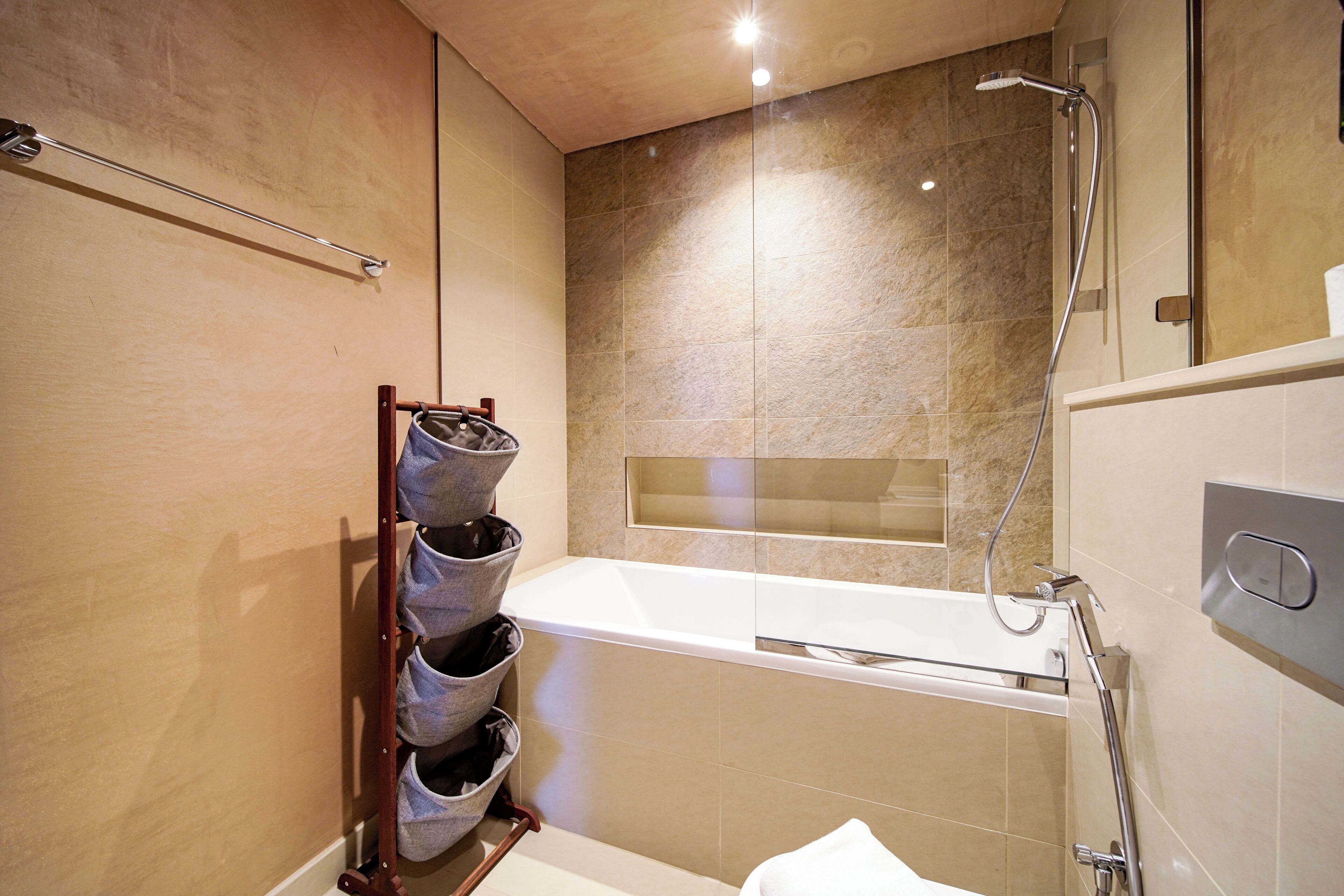 Ein modernes Badezimmer mit einer gläsernen Dusche, einer weißen Badewanne und einem Handtuchhalter mit mehreren Handtüchern.