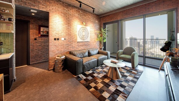A modern living room with a brick wall, a large window, and a checkered rug.