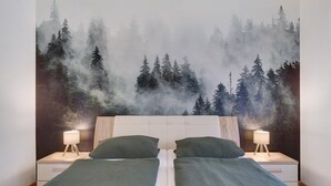 Een slaapkamer met een bed, twee nachtkastjes en een behangetje met een bosmotief.