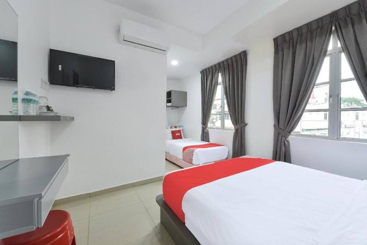 A hotel room with a bed, a desk, a TV, and a window with curtains.