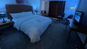 A hotel room with a large bed, a desk with a computer, a chair, and a TV. - Mayon Hotel (Riyadh)