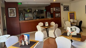 A hotel lobby with a reception desk, white chairs, tables, and a coffee machine. - Mayon Hotel (Riyadh)