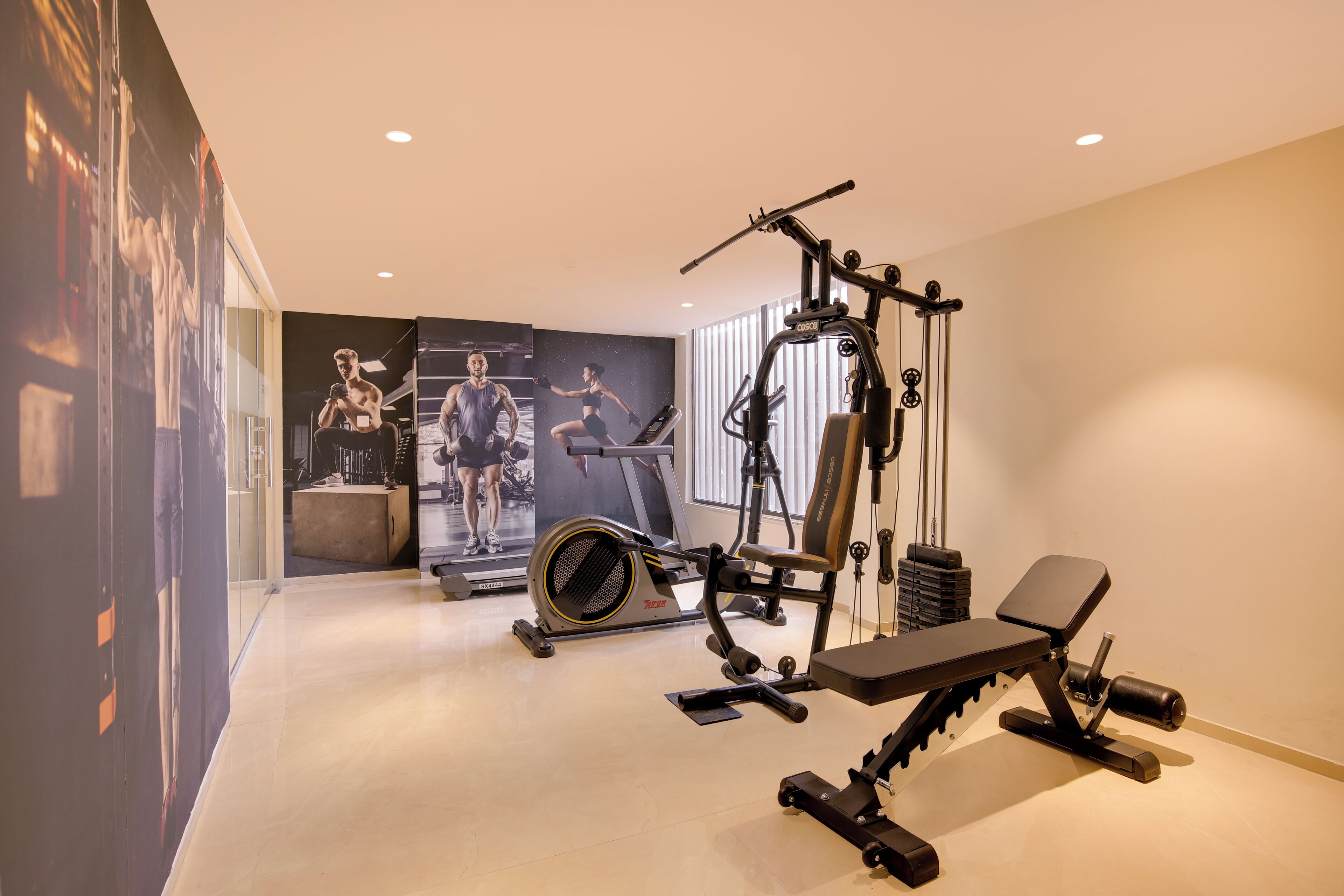 Un gimnasio en casa con cinta de correr, bicicleta estática y banco para pesas.