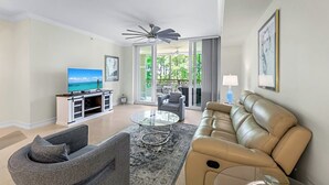 A modern living room with a leather sofa, a glass coffee table, and a TV on a wooden stand.