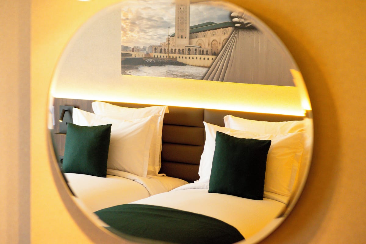 A hotel room with a bed, pillows, and a headboard.