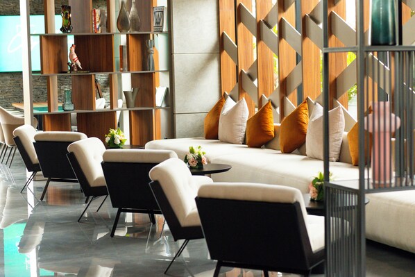 A modern lounge area with a sofa and chairs, a wooden bookshelf, and a decorative wall. - City Park Hôtel (Casablanca)