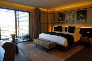 A modern hotel room with a large bed, a sitting area with a table and chairs, and artwork on the walls. - City Park Hôtel (Casablanca)