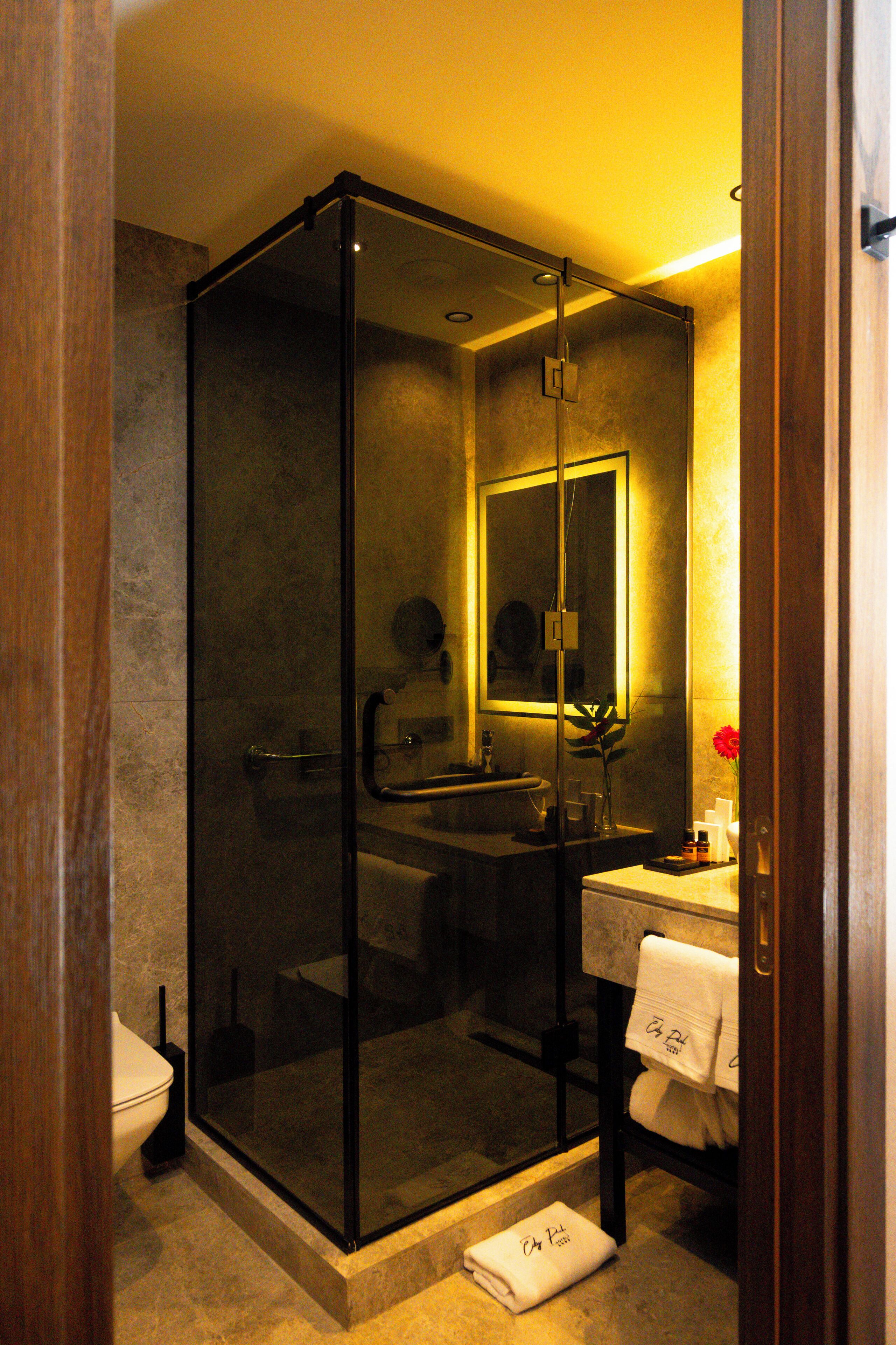 Un baño moderno con cabina de ducha de vidrio, un lavamanos con espejo y un perchero con toallas.