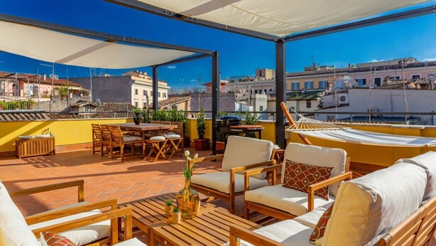 Una terraza en la azotea con mobiliario exterior, zona de comedor y vistas a la ciudad.