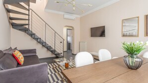 Una sala de estar moderna con una escalera, una mesa de comedor y un televisor montado en la pared.