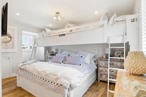 A bunk bed room with a ladder, a desk, and a chair.