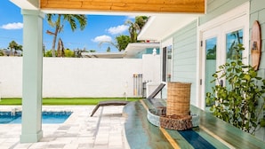 A covered outdoor area with a pool, a wicker basket, and a plant.